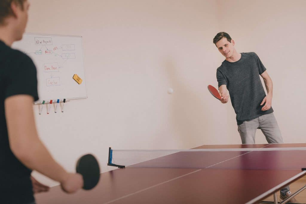 Two co-workers playing ping pong to take a work break. 