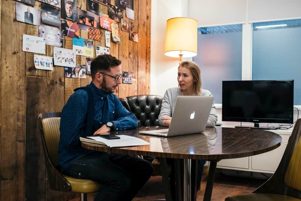 People talking over a laptop.