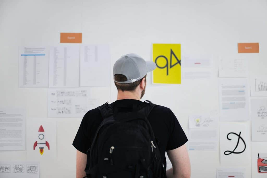 Man facing a white board with tasks and jobs. 